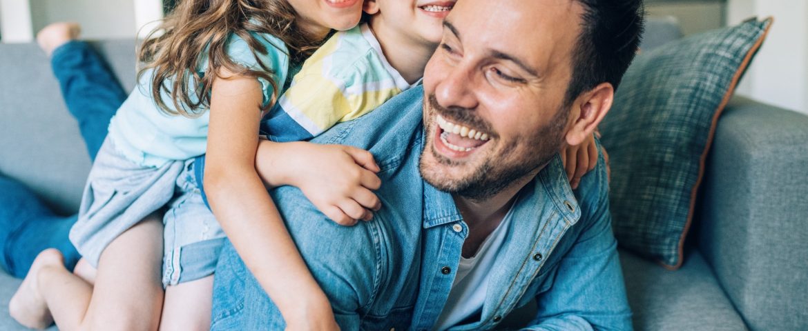 Happy Dad with son and daughter playing on couch