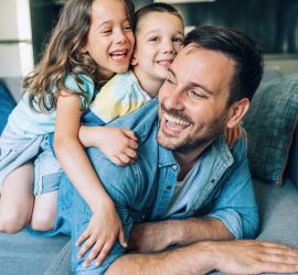 Happy Dad with son and daughter playing on couch