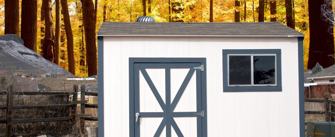 Organized garden shed by split rail fence and autumn foliage