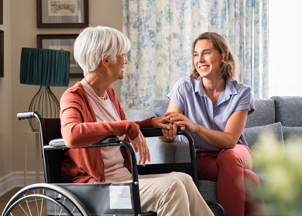 Mother in wheelchair with daughter holding her hand in living room